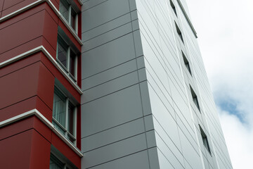 The exterior wall of a contemporary commercial style building with aluminum metal composite panels and glass windows. The futuristic building has engineered diagonal cladding steel frame panels.
