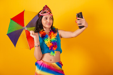 beautiful brazilian woman in carnival clothes, holding taking self portrait with smartphone