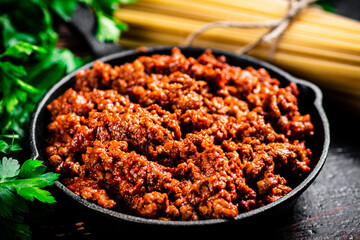 Bolognese sauce with parsley and dry pasta. 