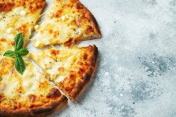 Italian pizza four cheeses with stretching cheese and basil on a light concrete background.