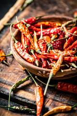 Dried chili peppers in a plate on a cutting board. 