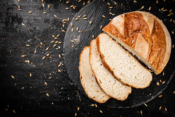 Sliced on a stone board wheat bread with grains. 