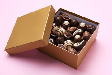 Open box of delicious chocolate candies on pink background