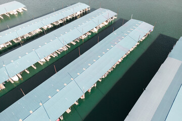 Aerial top down view of boat dock and yacht port, white private motor boats are moored on sea coast...