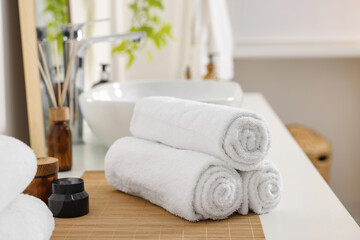 Naklejka na ściany i meble Rolled soft towels on white table in bathroom