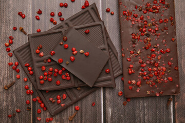 Delicious chocolate and red peppercorns on wooden table, flat lay