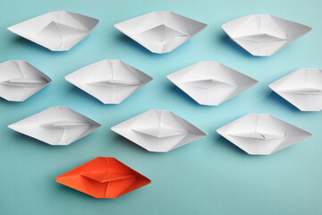 Orange paper boat among others on light background, flat lay. Uniqueness concept