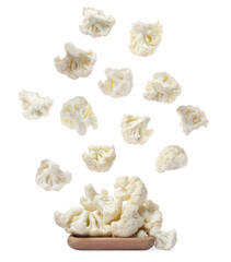 Many fresh cauliflower florets falling onto wooden plate on white background