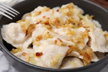 Cooked dumplings (varenyky) with tasty filling and fried onions in frying pan, closeup