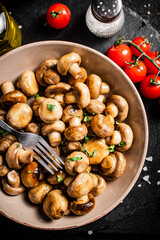 Fried mushrooms in a bowl with cherry tomatoes. 