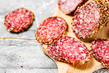 Cut into pieces of salami on a wooden cutting board. 