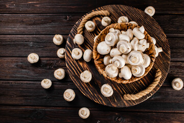 Fresh mushrooms in a basket on a wooden tray. 