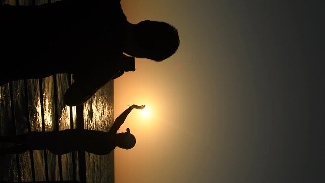 dos personas tomando foto en un atardecer en playas colombianas de tol&uacute; vide vertical