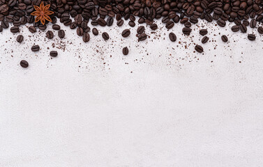Dark roasted coffee beans setup on white concrete background with copy space.