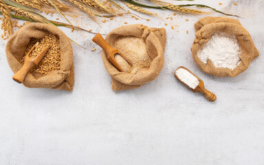 Wheat ears and wheat grains set up on white stone background.