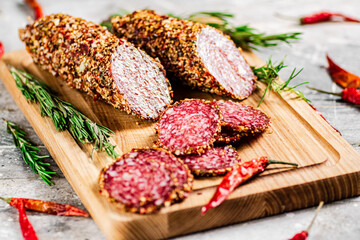 Cut into pieces of salami on a wooden cutting board. 