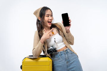 Happy Asian woman traveler showing smartphone screen with luggage, camera, passport and boarding pass ticket isolated on white background, Tourist girl having cheerful holiday trip concept.