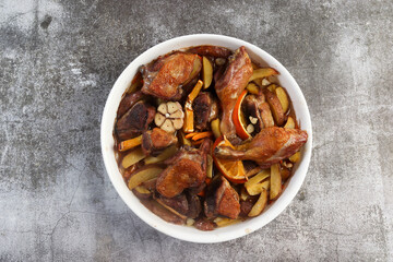 Oven baked Duck with potatoes and carrots in a white baking dish on a dark grey background. Top view, flat lay
