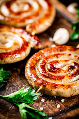 Grilled sausages with garlic and parsley on a wooden background.