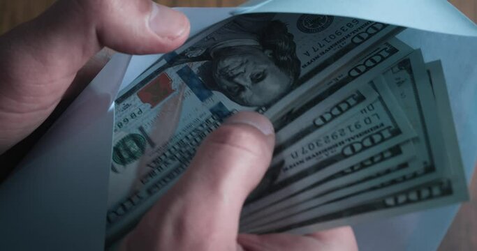 Person counting money cash from envelope closeup. Illegal business deal with cash money for tax evasion. Dirty money cash salary in envelope Closeup male hands counting 100 dollar bills from envelope.