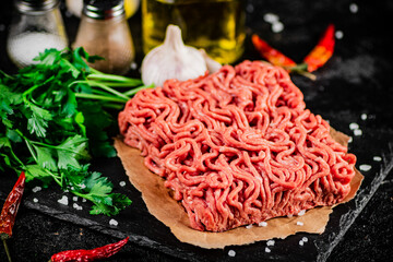 Minced meat on a stone board with parsley and garlic. 