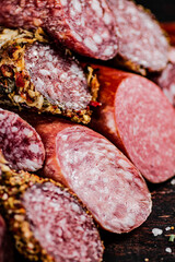 Slices of various salami in a pile on the table. 