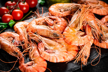 Boiled shrimp on a stone board with tomatoes and parsley.