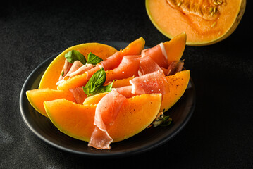 melon with parma on a dark background