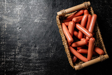 A bunch of sausages boiled in a box on the table. 