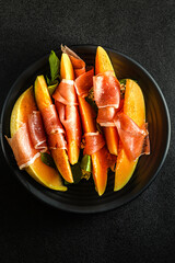 melon with parma on a dark background