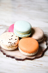 Macaron pink, orange and beige, blue on marble style. A beautiful and beautiful French dessert. Fruits and epoxy resin and flowers on the background