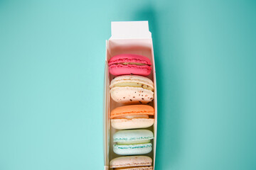 Colorful macarons. Small French cakes. Sweet and colorful french macarons in a box on a blue background. Gift for Valentine's Day.