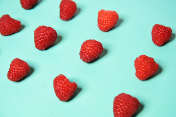 Raspberry pattern on the blue color of the lagoon. Fruits and healthy food, trendy photo.