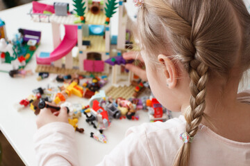 Little cute girl spending time in the playroom with a constructor, soft focus background