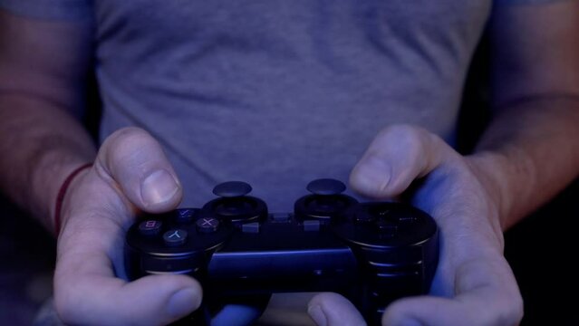 Male hands are playing game joystick, controller or joypad of game console