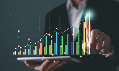 Businessman use tablet  hand holding  virtual increasing technical graph and up arrow for trader analysis to searching the best business growth and profit return from stock market chart concept.