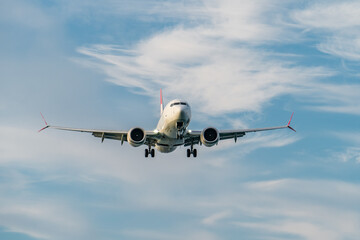 Commercial passenger airplane arrives at airport against blue sky with clouds.