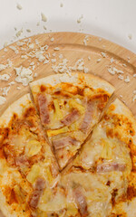 Closeup top view studio shot of tasty delicious Italian homemade mozzarella cheesy ham pineapple original Hawaiian pizza soft bread crust on wodden plate served on table in restaurant.
