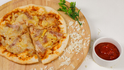 Closeup top view studio shot of tasty delicious Italian homemade mozzarella cheesy ham pineapple original Hawaiian pizza soft bread crust on wodden plate served on table with ketchup in restaurant