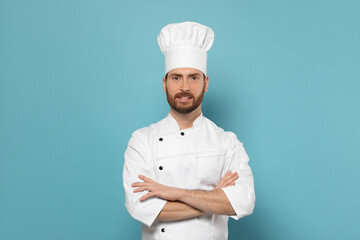 Smiling mature chef on light blue background, space for text