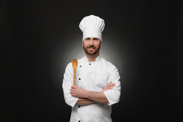 Mature chef with spoon on black background