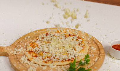 Closeup studio shot of hot oven baked tasty delicious Italian homemade ham pineapple original soft bread crust pizza on wooden plate pan while sprinkling mozzarella cheese on top with tomato ketchup