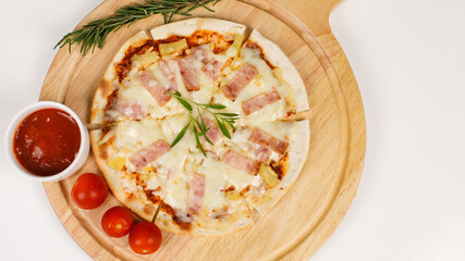 Closeup top view studio shot of round hot oven baked tasty delicious Italian homemade ham pineapple original Hawaiian soft bread crust pizza on wooden plate pan with tomatoes and ketchup on table