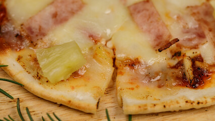 Closeup top view studio shot of round hot oven baked tasty delicious Italian homemade ham pineapple original Hawaiian soft bread crust pizza on wooden plate pan with tomatoes and ketchup on table