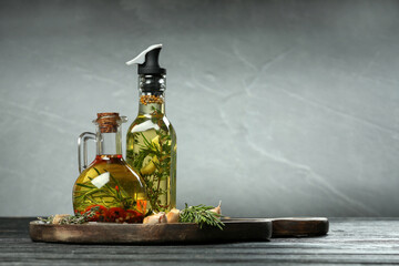 Cooking oil with different spices and herbs in bottles on dark wooden table. Space for text