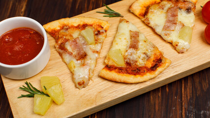 Closeup top view studio shot of three pieces of hot oven baked tasty delicious Italian homemade ham and pineapple Hawaiian soft bread crust pizza decorated on wooden plate pan with tomatoes ketchup