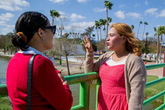 Amigas platicando frente a un barandal en el parque. Chica escuchando con atencion a su compa&ntilde;era
