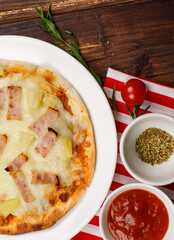 Closeup top view studio shot of multiple hot oven baked tasty delicious Italian homemade ham pineapple traditional Hawaiian bread crust pizzas placed on white dishes ready to serve in restaurant