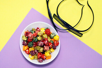 Colorful popcorn with 3D glasses on a purple and yellow background