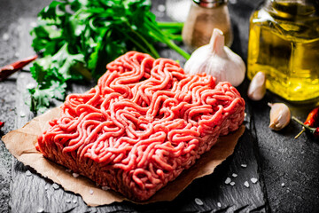 Minced meat on a stone board with parsley and garlic. 